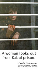 A woman looks out from Kabul prison.