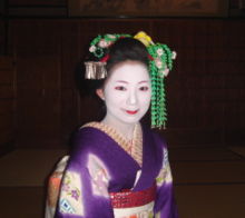 The maiko Mamechiho in the Gion district of Kyoto. Notice the green pin on the mid-left: this identifies her as a maiko of Gion-Higashi.