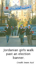 Jordanian girls walk past an election banner.