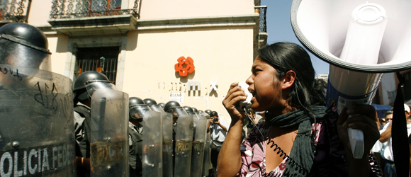 A protester uses a megaphone in front of Federal police officers in Oaxaca city's main plaza