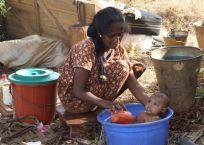 Displaced mother washing her baby in Sri Lanka