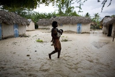 A woman carries a child through flooded roads caused by Tropical ...