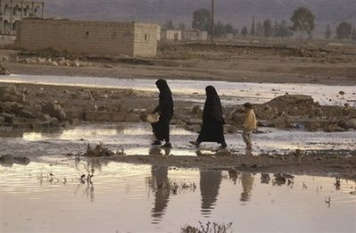 Yemenis walk on a partially flooded area of Maabar, south of ...