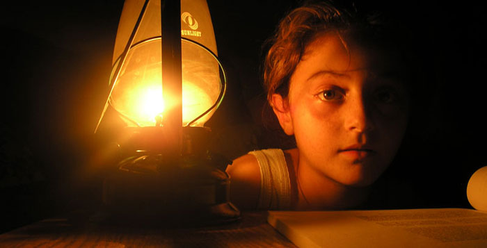 Young girl reads by candlelight