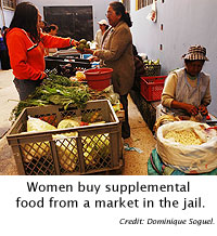 Women buy food from a market in the jail.