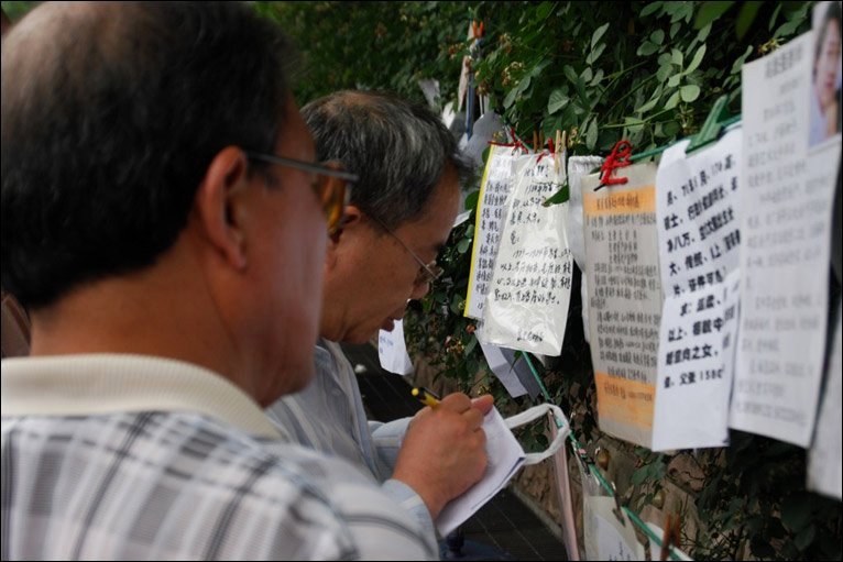 People writing down details from notices in People's Park, Shanghai