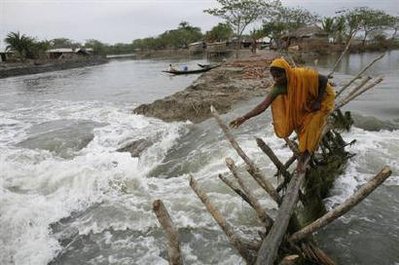 A woman crosses a bamboo made bridge over a breached dam caused ...