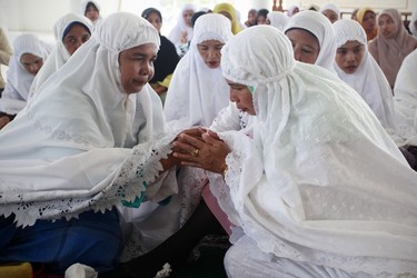 BANDA ACEH, INDONESIA - DECEMBER 25:  Acehnese women comfort each other while taking part in a mass  prayer for the victims of the Indian Ocean tsunami of 2004 in the Mosque Rahmatullah December 25, 2009 in Banda Aceh, Indonesia. The mosque was the only building left standing after the tsunami in Lampuuk on December 25, 2004. It is seen on the fifth anniversary of the 2004 Boxing Day earthquake and subsequent tsunami. Aceh was the worst hit location, being the closest major city to the epicentre of the 9.1 magnitude quake. The city suffered a huge hit from the resulting tsunami which caused around 130,000 deaths. Throughout the affected region of eleven countries roughly 225,000 people in total were killed, making it one of the deadliest natural disasters in recorded history.