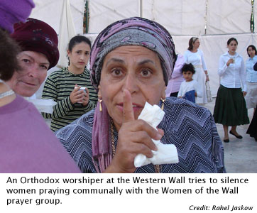 An Orthodox worshiper at the Western Wall tries to silence women praying communally with the Women of the Wall prayer group.