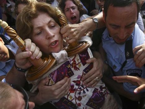 Anat Hoffman, chairwoman of the Women of the Wall group, holds on to a Torah scroll as police attempt to take it from her and detain her outside the Western Wall, July 12, 2010