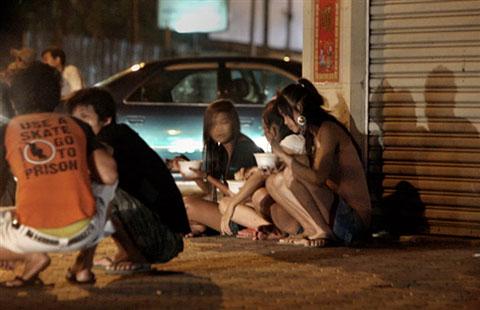 Cambodian sex workers sit on a sidewalk in a street of Phnom Penh (2008 file photo) 