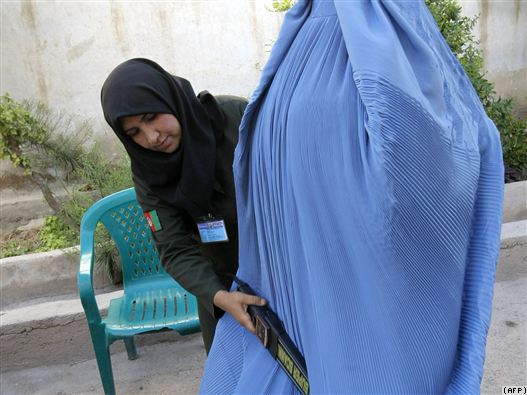 An Afghan policewoman searches a burqa-clad woman entering a polling station in Herat in August 2009 voting.