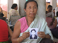 Manipur woman holds up a photo of a loved one, killed by gun violence