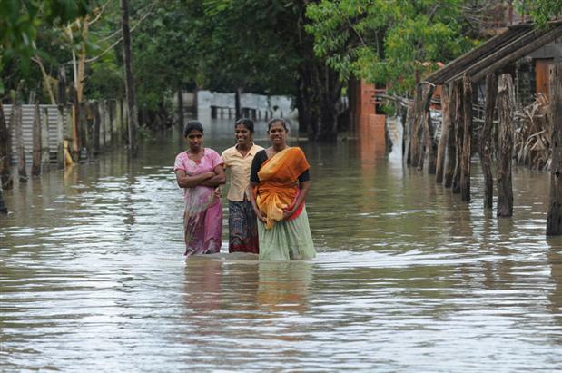 Sri Lankan flood affected women wade through the waters of a flooded street of the eastern Sri Lankan town of Batticaloa on January 14, 2011. The number of people killed in Sri Lanka's monsoon flooding and mudslides has risen to 27 with more than a million people still displaced by the devastating disaster, officials said.
