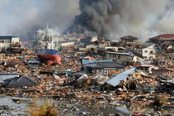 Carnage: Amidst tsunami flood waters burning houses and ships are piled in a mass of debris in Kisenuma city, Miyagi prefecture