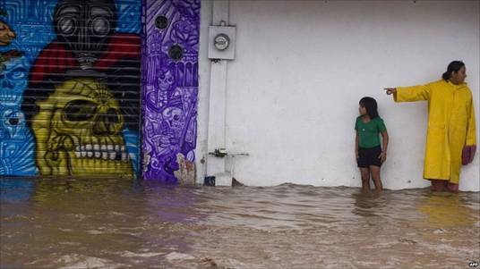 Locals wait to cross a flooded street, following the passage of Jova Hurricane in the region, in Manzanillo, Colima State, Mexico, on 12 October 2011.