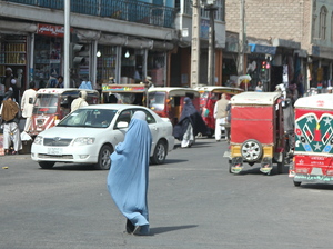 A woman crosses the street in Herat, Afghanistan. Burqa-clad women stand out on the streets in Afghanistan — both because of their bright blue burqas, and because there are far fewer women in public than men.