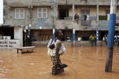 A woman with a baby on her back wades through water after flooding on a street in Senegal&apos;s capital Dakar, Aug. 14, 2012. REUTERS/Joe Penney