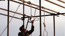 A soldier prepares a noose ahead of a public hanging.