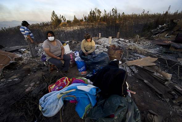 A family sits amid the ruins of their house in an area ravaged by fire