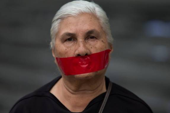 A woman with tape over her mouth in protest of officials breaking up protesters' camps, stands outside the United Nations headquarters in Caracas, Venezuela, Thursday, May 8, 2014. Hundreds of security forces broke up four camps maintained by student protesters, arresting 243 people in a Thursday pre-dawn raid. (AP Photo/Fernando Llano)