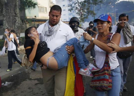 Demonstrators help a girl overcome by tear gas as protest against the government of President Nicolas Maduro in Caracas, February 22, 2014. REUTERS-Carlos Garcia Rawlins