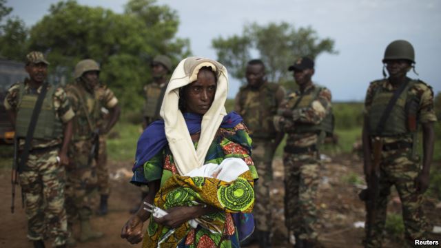 FILE - The relative of a woman that recently gave birth yesterday to twins holds one of the babies before departing towards Chad's border, escorted by troops from the African Union operation in CAR (MISCA) in the northern town of Kaga Bandoro.