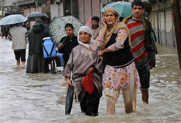 A Kashmiri woman speaks on the phone as she wades through floodwaters with others in Srinagar, India, Thursday, Sept. 4, 2014. Authorities say heavy rains have triggered floods and landslides in the Indian portion of Kashmir, killing at least 14 people in the worst flooding in 22 years.