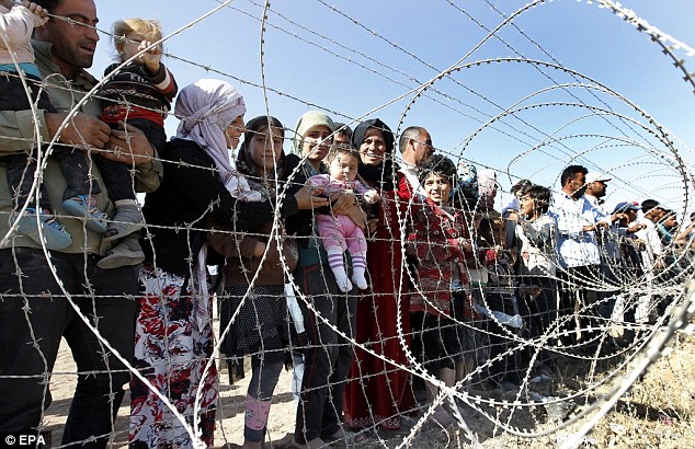 Syrian refugees wait behind barbed wire near the Turkish-Syrian border