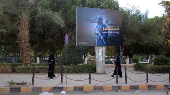 Women wearing a niqab, a type of full veil, walk under a billboard erected by the Islamic State (IS) group as part of a campaign in the IS-controlled Syrian city of Raqqa on November 2.