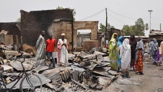 People stand outside burnt houses following an attack by Islamic militants in Gambaru, Nigeria (11 May 2014)