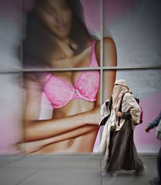 A woman in hijab walks past a lingerie ad.