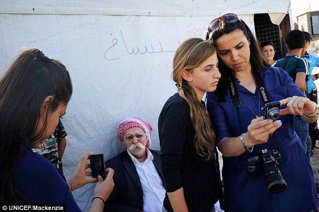 Talent: Photography student Bushra (second from right), 16, stands listening to Seiven, her instructor, as she reviews a portrait she has just taken of the man sitting behind her